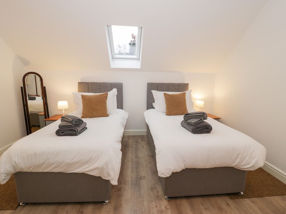 A bedroom with two single beds and a mirror at Merddwr in Cerrigydrudion