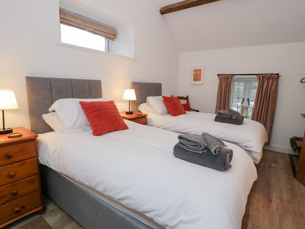 A bedroom with two beds and a window at Merddwr in Cerrigydrudion