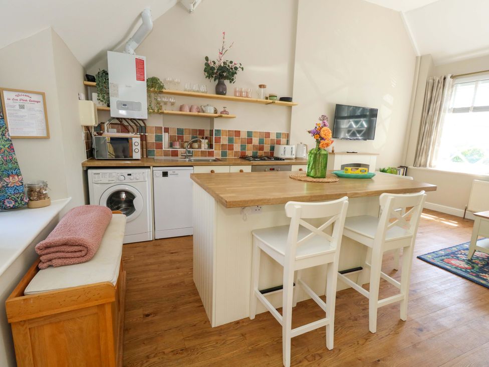 A kitchen with appliances and seating at Sea Pink Cottage in Langton Matravers