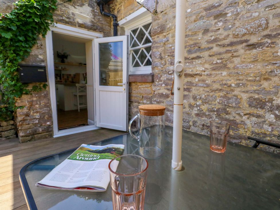 An outdoor seating area with a table and glasses at Sea Pink Cottage in Langton Matravers