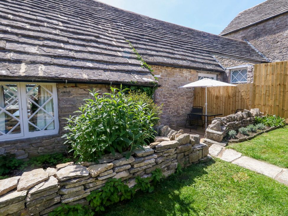 A garden with a stone wall and chairs at Sea Pink Cottage in Langton Matravers