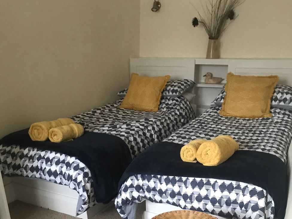 A bedroom with two single beds and towels at Tyee Cottage in Burton-In-Kendal