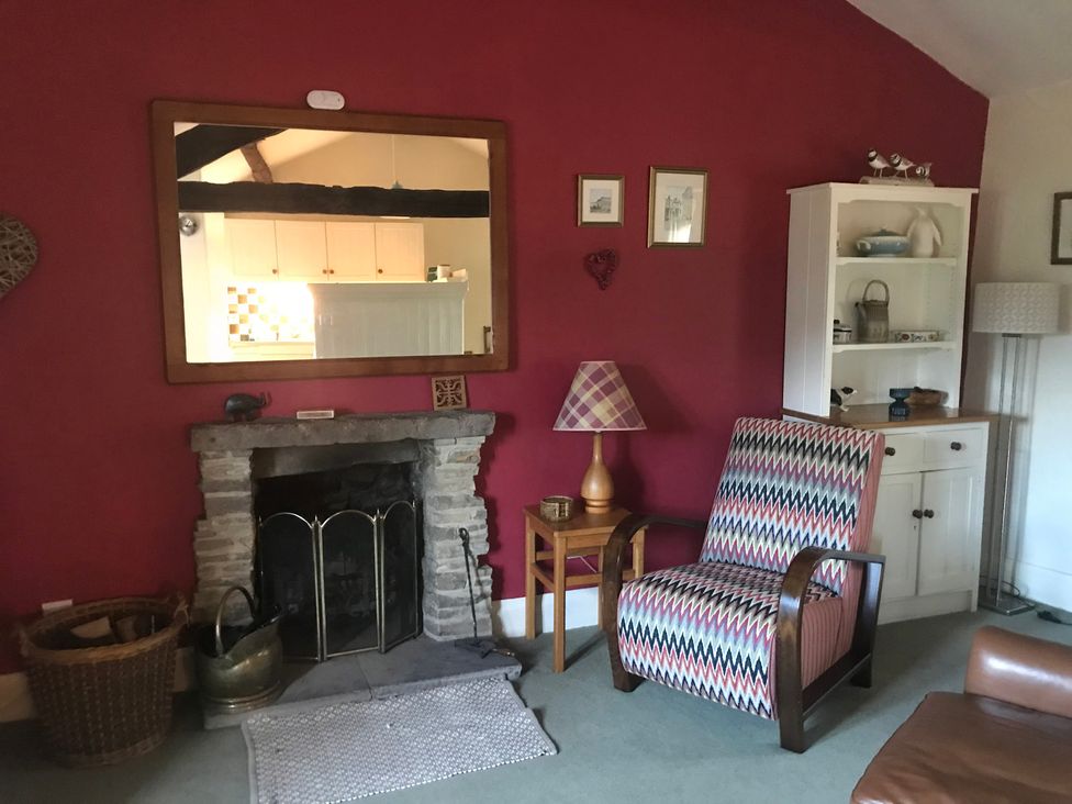 A living room with a fireplace and a bookshelf at Tyee Cottage Burton-In-Kendal