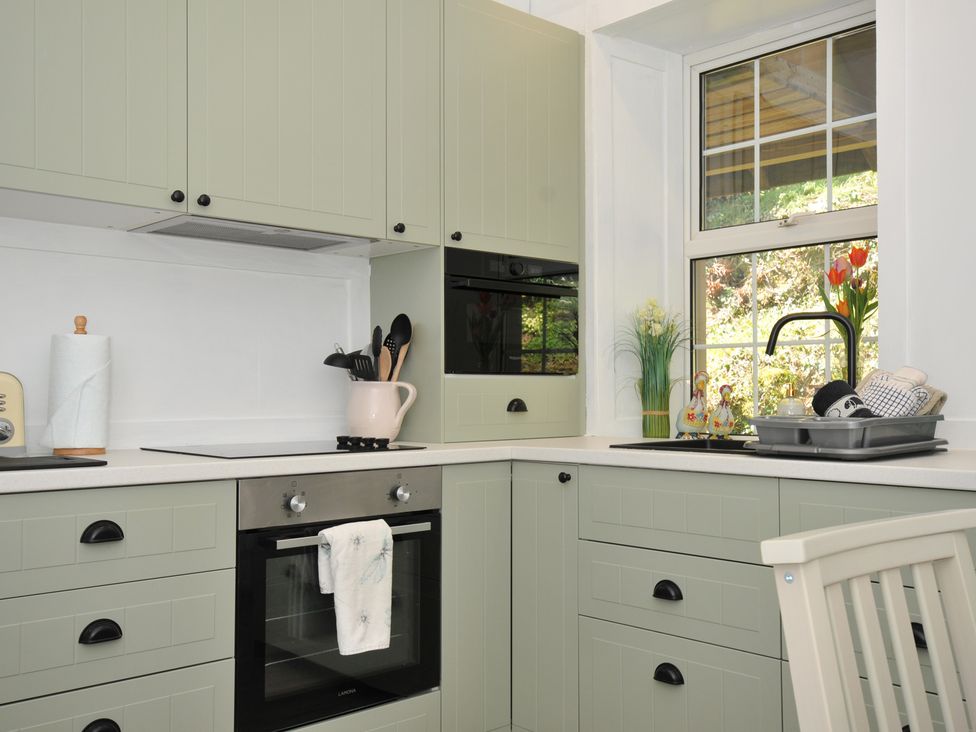 A kitchen with cabinets, oven, and sink at Tor View @ Fourwinds, Meldon near Okehampton