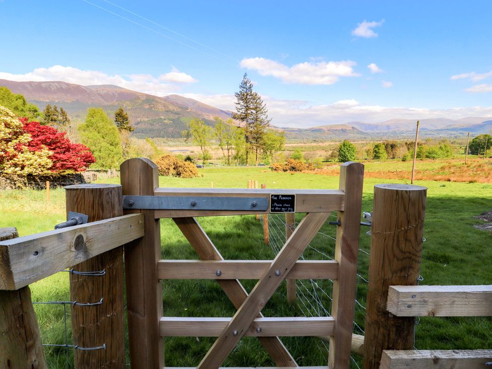 A wooden gate opening to a field with mountains in the background at Swallow's Nest Thornthwaite near Braithwaite