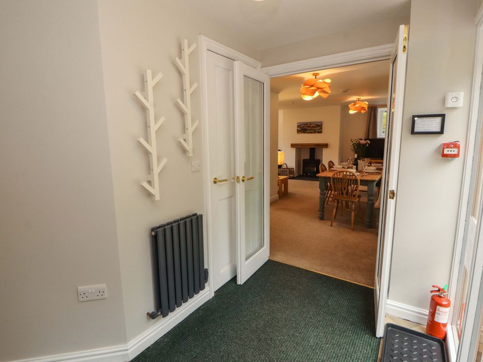 A hallway with coat racks and doors leading to another room at Swallow's Nest Thornthwaite near Braithwaite