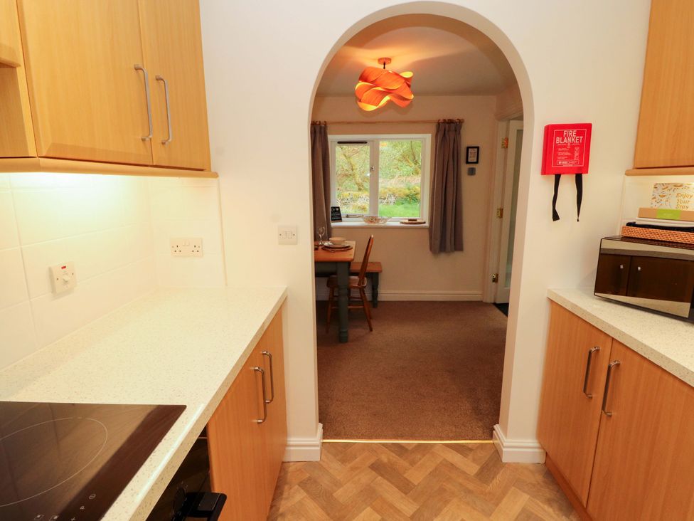 A kitchen with cabinets and a dining table at Swallow's Nest Thornthwaite near Braithwaite