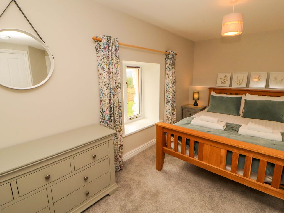 A bedroom with a bed and dresser at Swallow's Nest Thornthwaite near Braithwaite