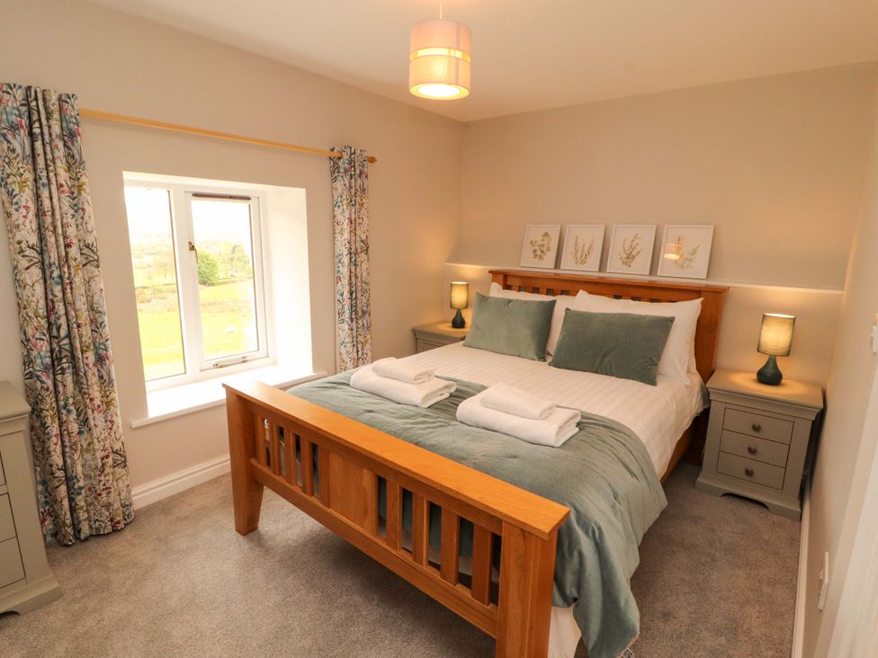 A bedroom with a bed and bedside tables at Swallow's Nest in Thornthwaite near Braithwaite