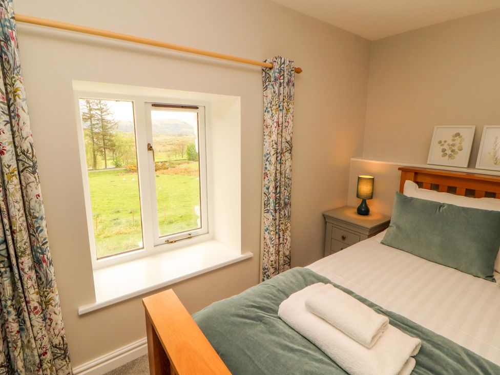 A bedroom with a bed and window at Swallow's Nest Thornthwaite near Braithwaite