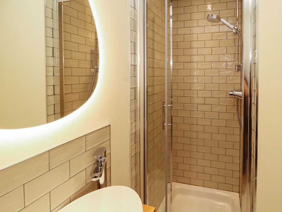 A bathroom with a shower, sink, and mirror at Swallow's Nest Thornthwaite near Braithwaite