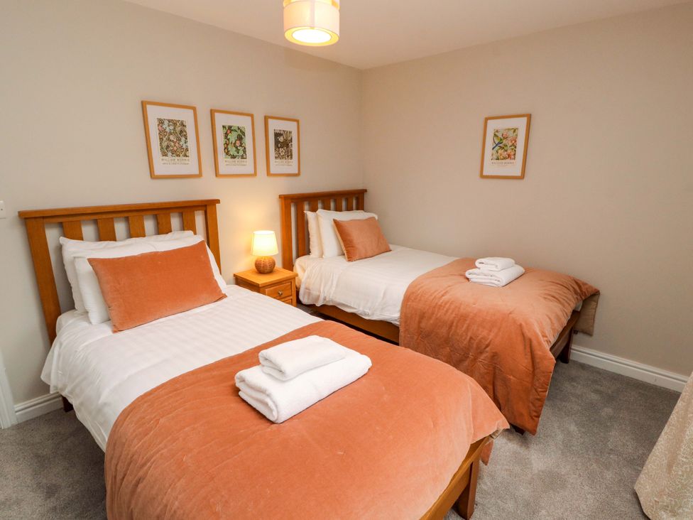 A bedroom with two beds, a lamp and artwork at Swallow's Nest Thornthwaite near Braithwaite