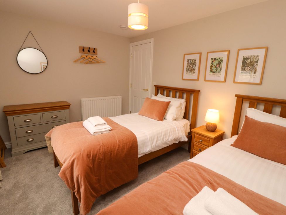 A bedroom with two single beds and a dresser at Swallow's Nest Thornthwaite near Braithwaite
