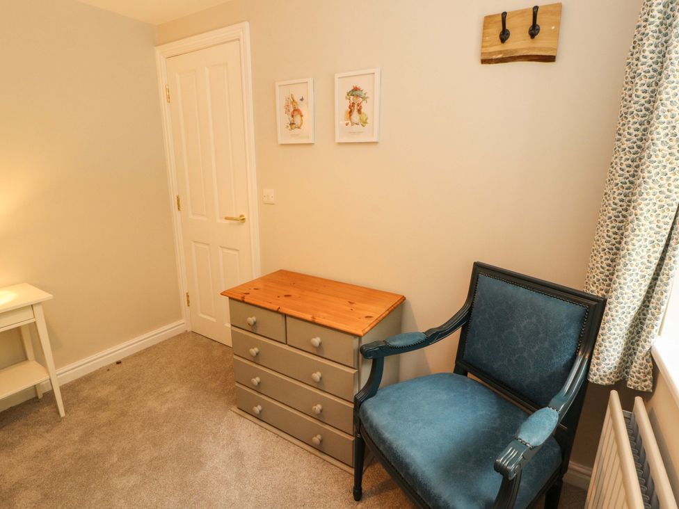 A bedroom with a chest of drawers and an armchair at Swallow's Nest in Thornthwaite near Braithwaite