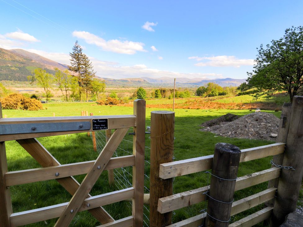 A view of a field with a gate and mountains in the background at Swallow's Nest Thornthwaite near Braithwaite