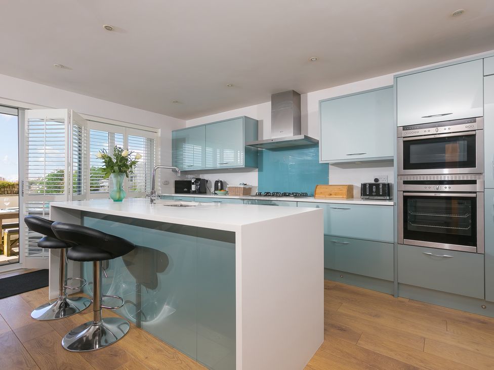 A kitchen with an island and bar stools at Sandbanks in Praa Sands