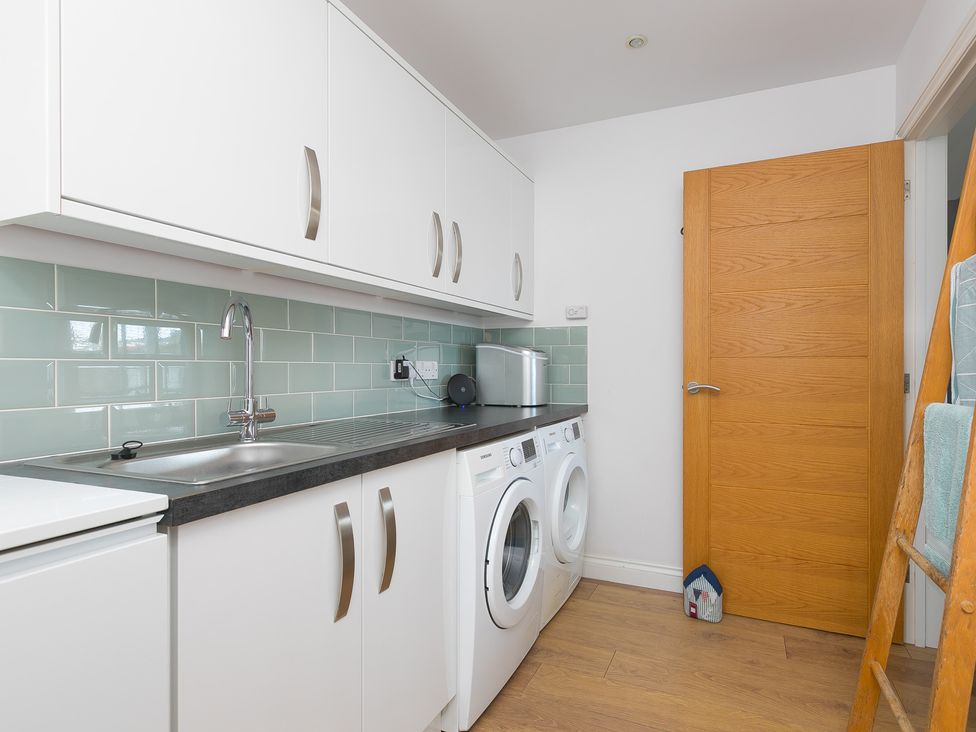 A laundry room with a sink and washing machine at Sandbanks in Praa Sands