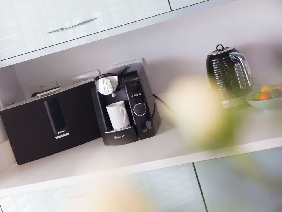 A kitchen with coffee maker, kettle, speaker, and bowl of fruit at Sandbanks in Praa Sands