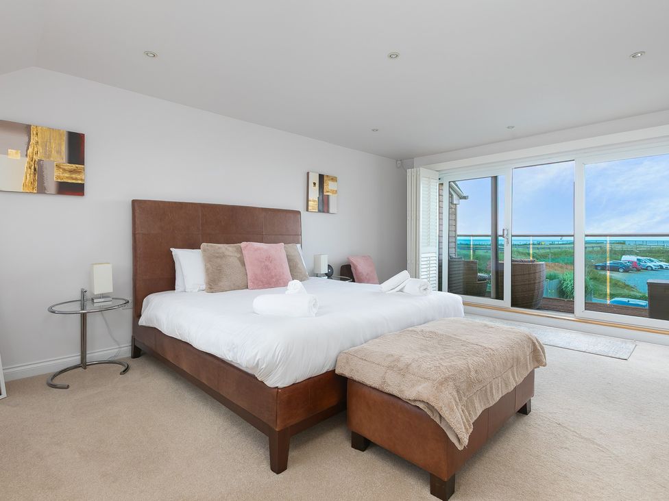 A bedroom with a bed and side table at Sandbanks in Praa Sands