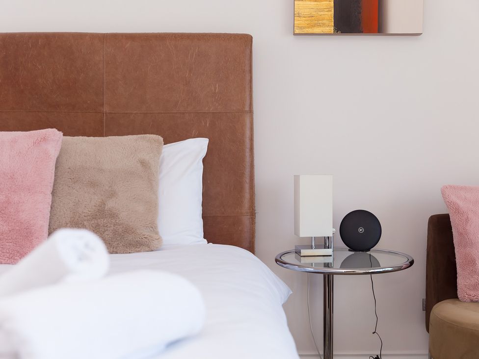 A bedroom with a bed and side table at Sandbanks in Praa Sands