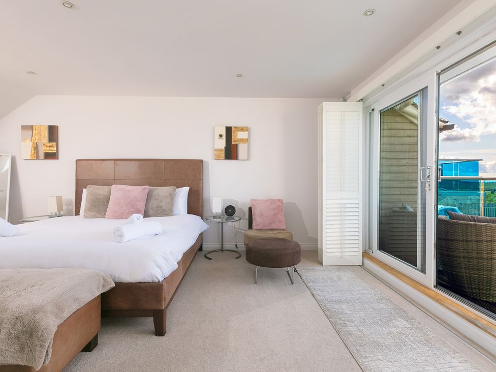 A bedroom with a bed and chair at Sandbanks in Praa Sands