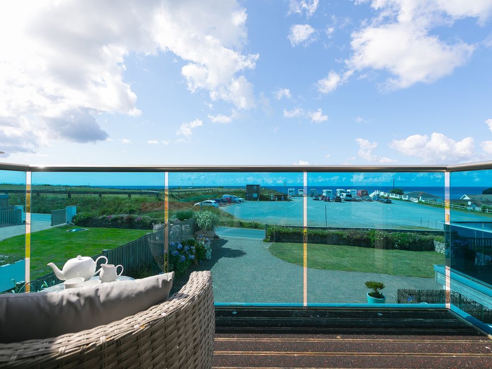 An outdoor balcony with a teapot and cup overlooking a parking area at Sandbanks in Praa Sands