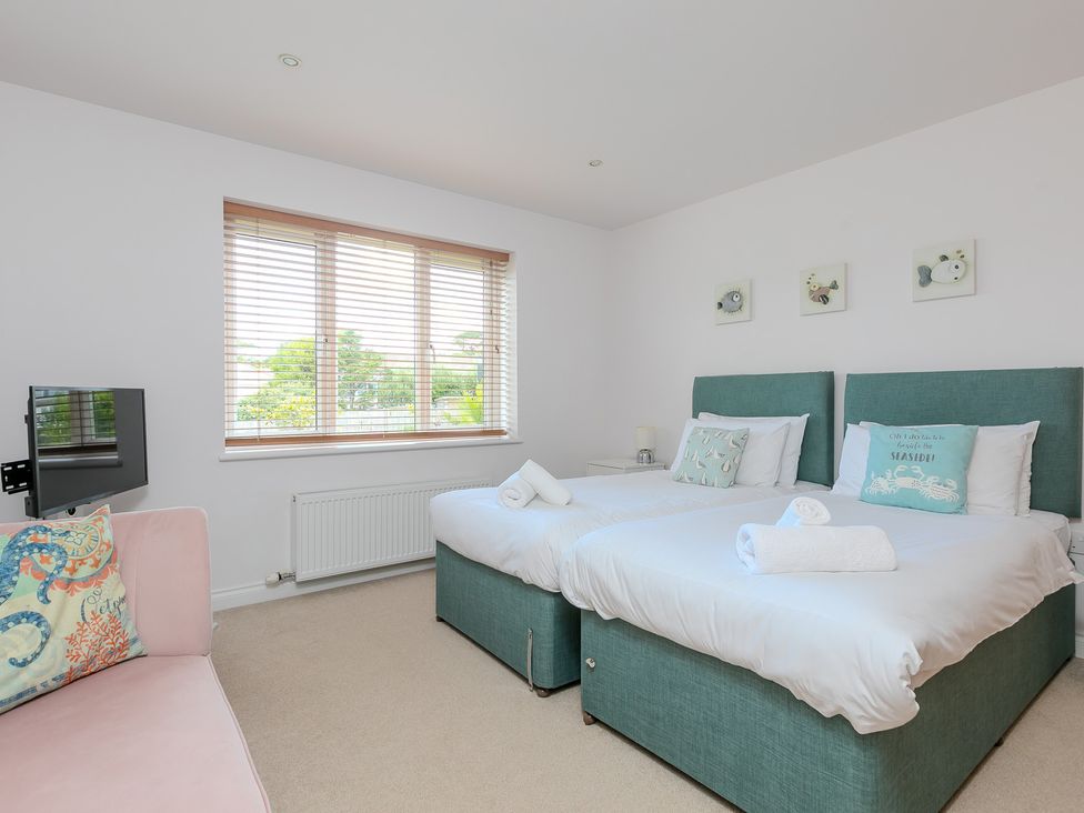 A bedroom with twin beds and a television at Sandbanks in Praa Sands