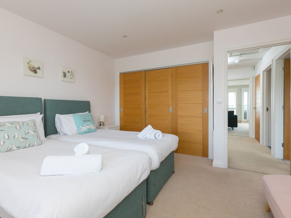 A bedroom with two beds and a wardrobe at Sandbanks in Praa Sands