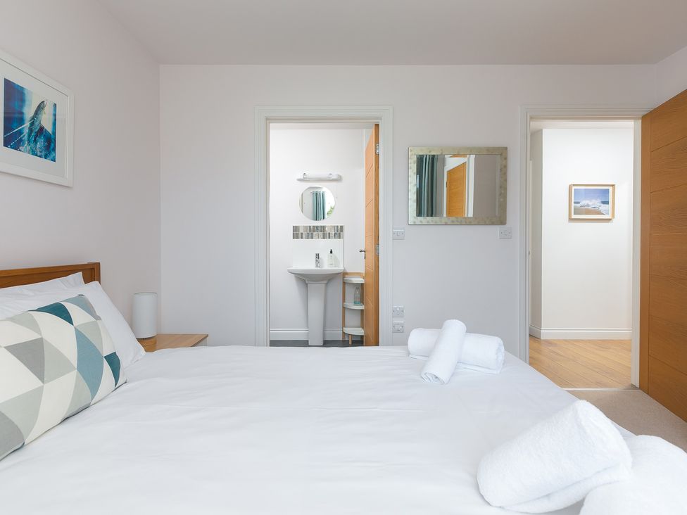 A bedroom with a bed and wash basin at Sandbanks in Praa Sands