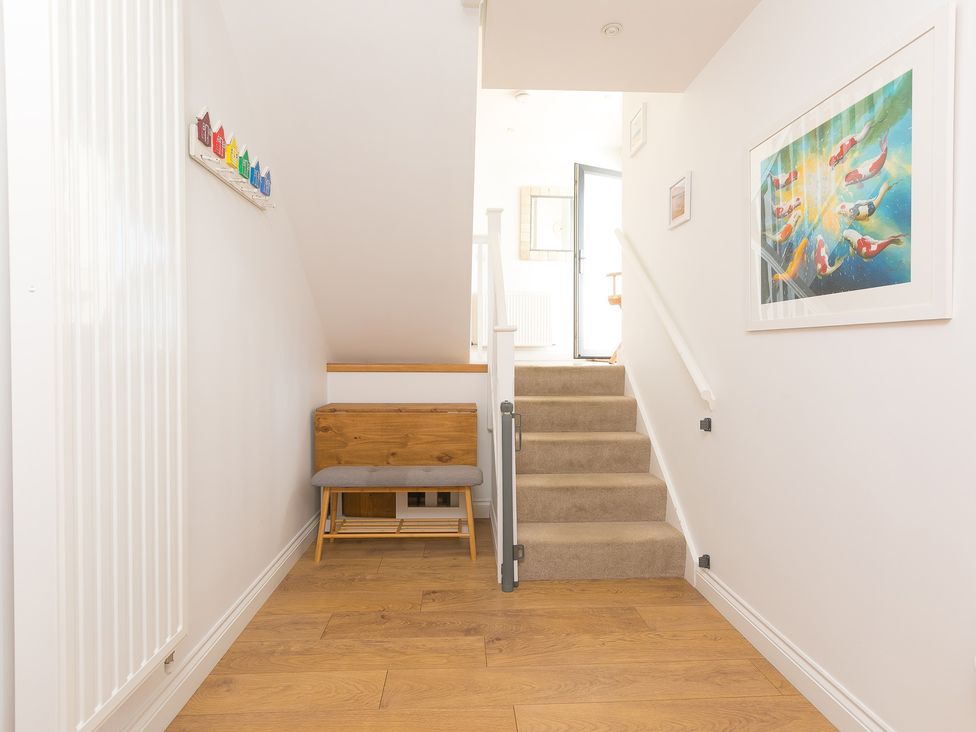 A hallway with a staircase and a bench at Sandbanks in Praa Sands