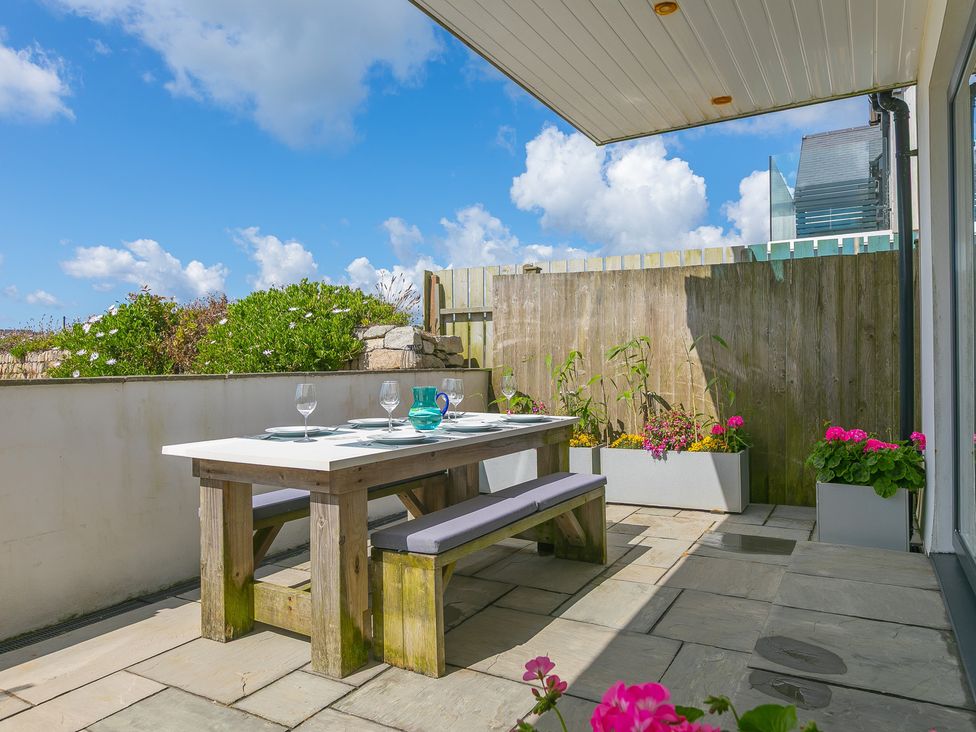 An outdoor dining area with a table and benches at Sandbanks Praa Sands