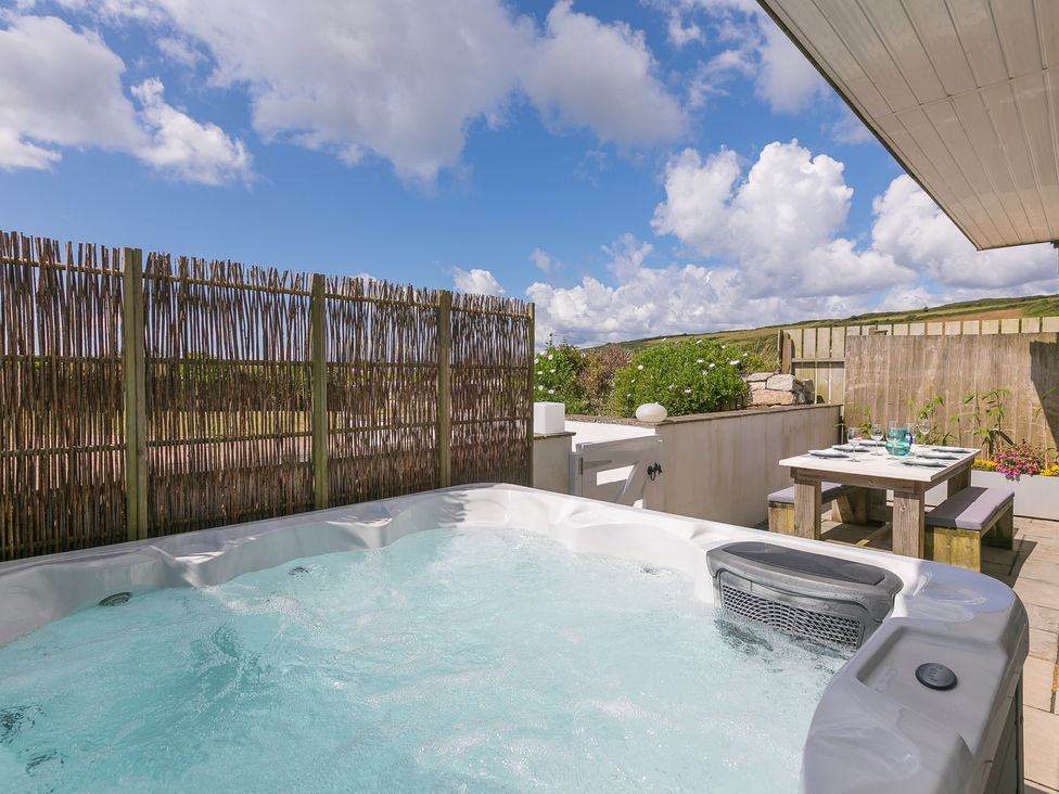 An outdoor area with a hot tub and table at Sandbanks in Praa Sands