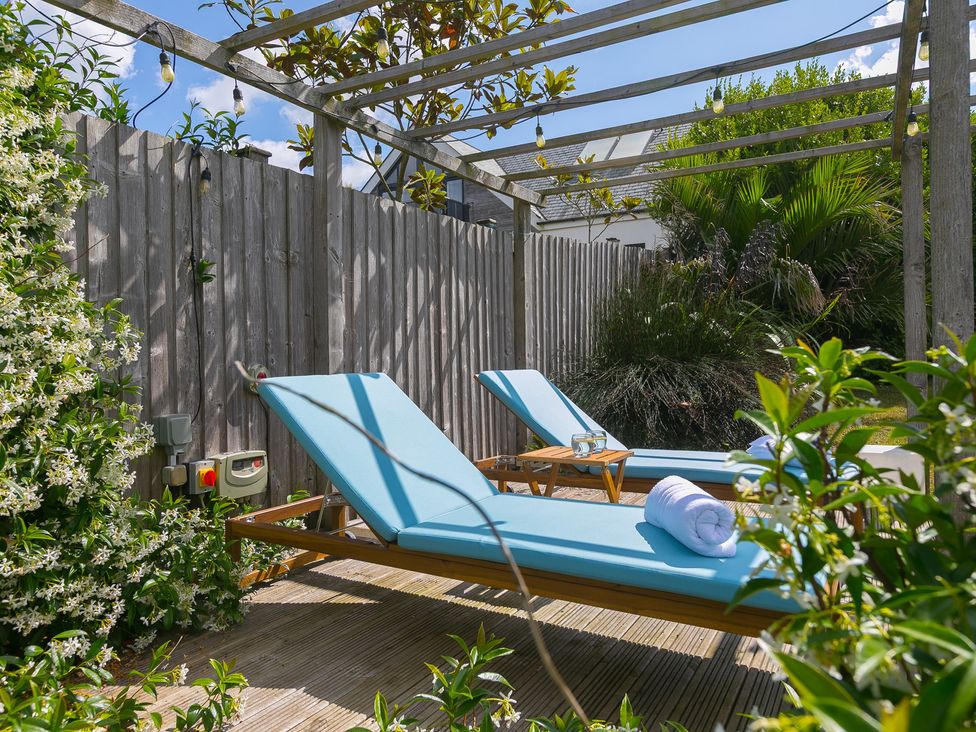 A garden with sun loungers and a table at Sandbanks in Praa Sands