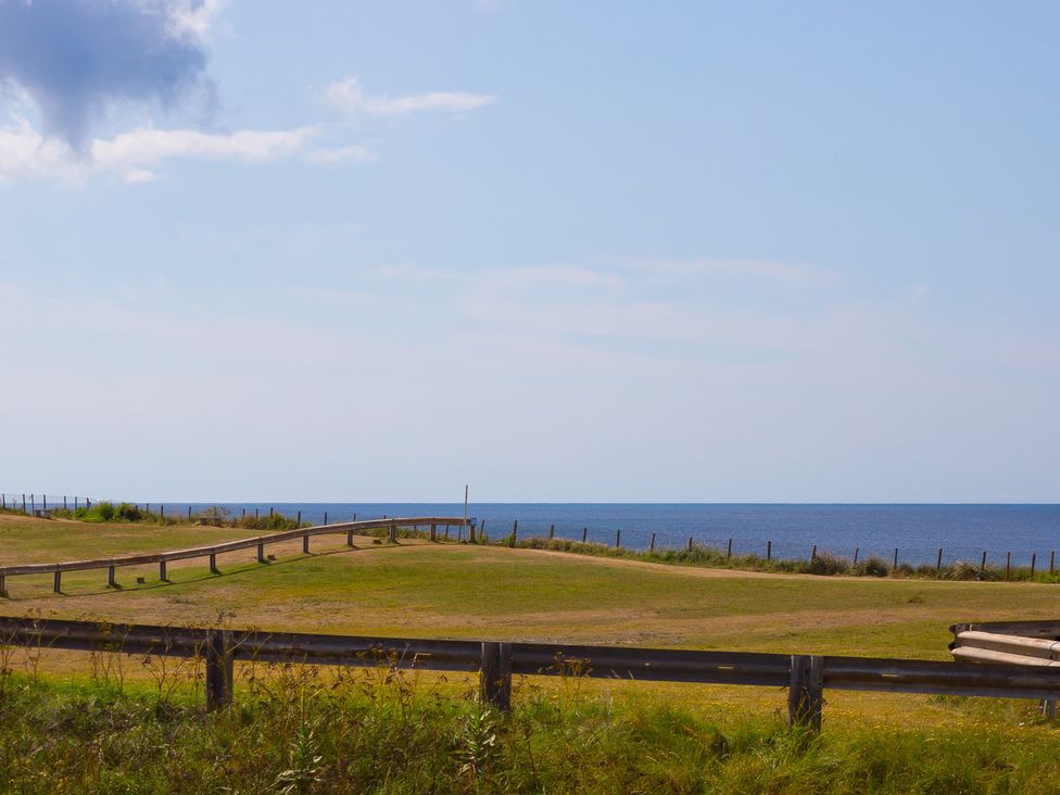 A view of grass and ocean with a wooden fence at Sandbanks, Praa Sands