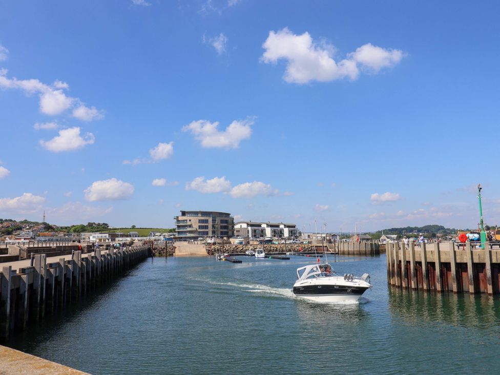 A marina with a boat entering water near the pier at West Bay Holiday Home in West Bay