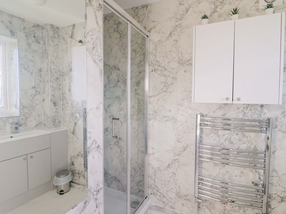A bathroom with a shower and sink at West Bay Holiday Home in West Bay
