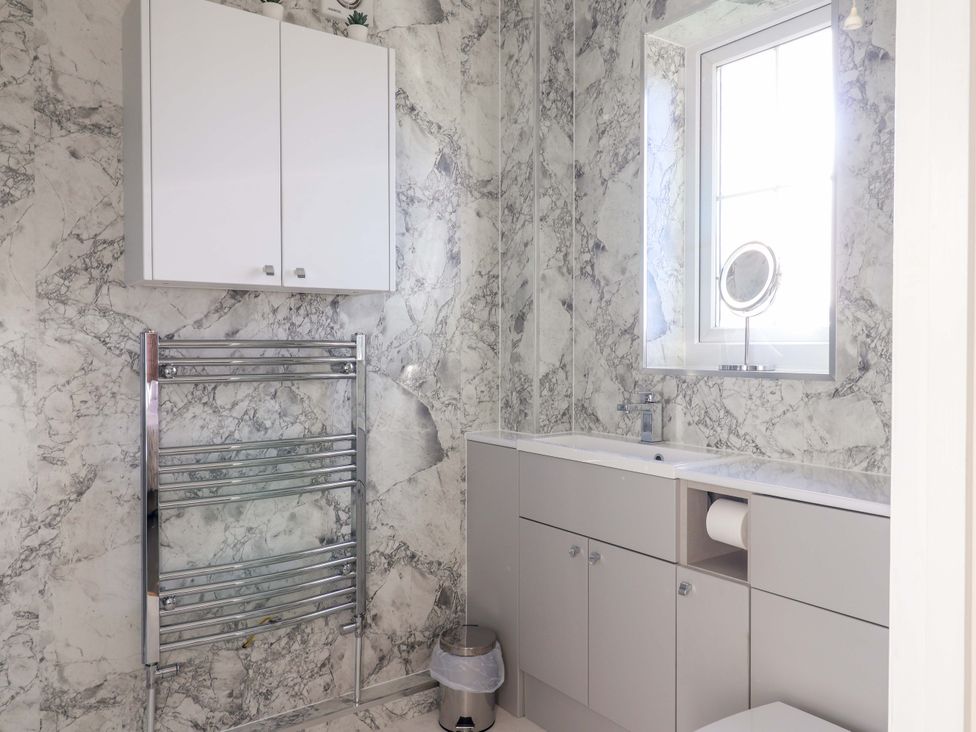 A bathroom with a sink and cabinet at West Bay Holiday Home in West Bay