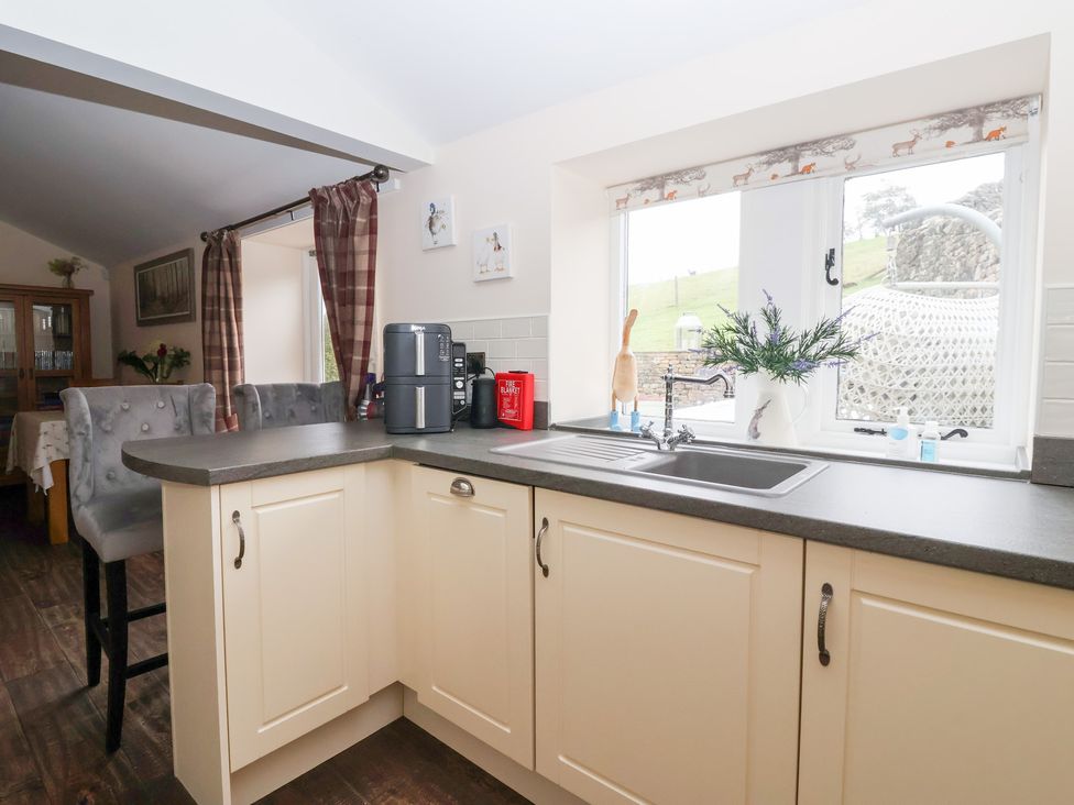 A kitchen with cabinets and a sink at Beckside Cottage Cowling near Skipton