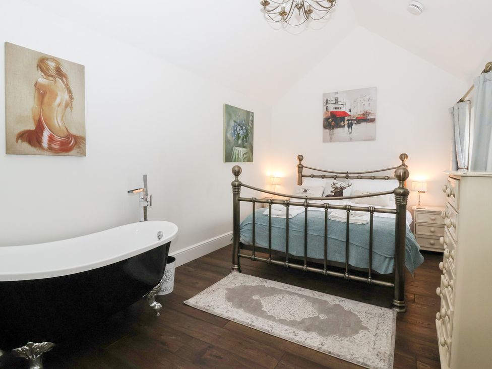 A bedroom with a bed and a bathtub at Beckside Cottage in Cowling near Skipton