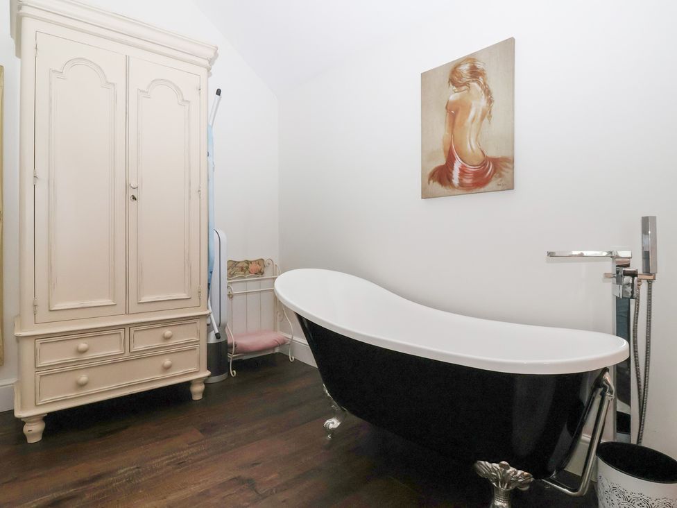 A bathroom with a bathtub and wardrobe at Beckside Cottage in Cowling near Skipton