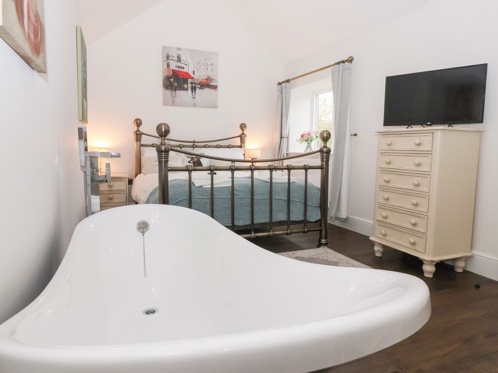 A bedroom with a bed and a bathtub at Beckside Cottage in Cowling near Skipton