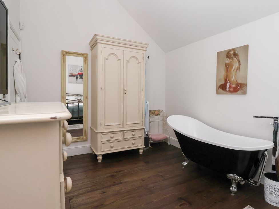 A bathroom with a bathtub and wardrobe at Beckside Cottage Cowling near Skipton