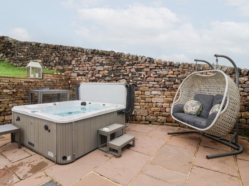 A hot tub with a hanging chair at Beckside Cottage in Cowling near Skipton