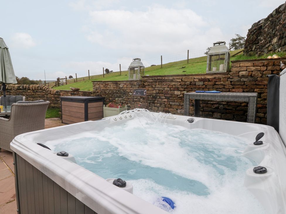 A hot tub with outdoor furniture at Beckside Cottage in Cowling near Skipton