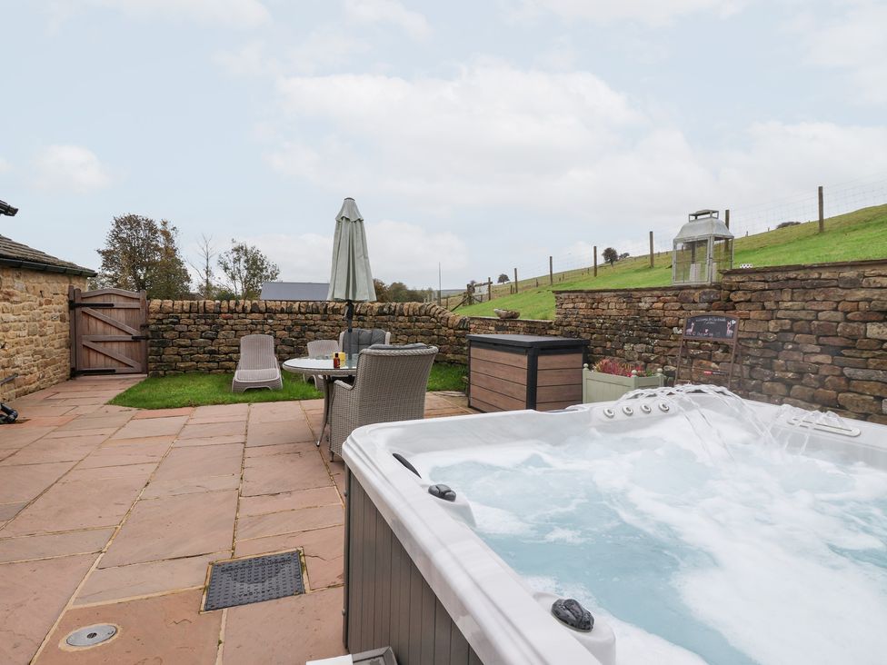 An outdoor area with a hot tub and seating at Beckside Cottage in Cowling near Skipton