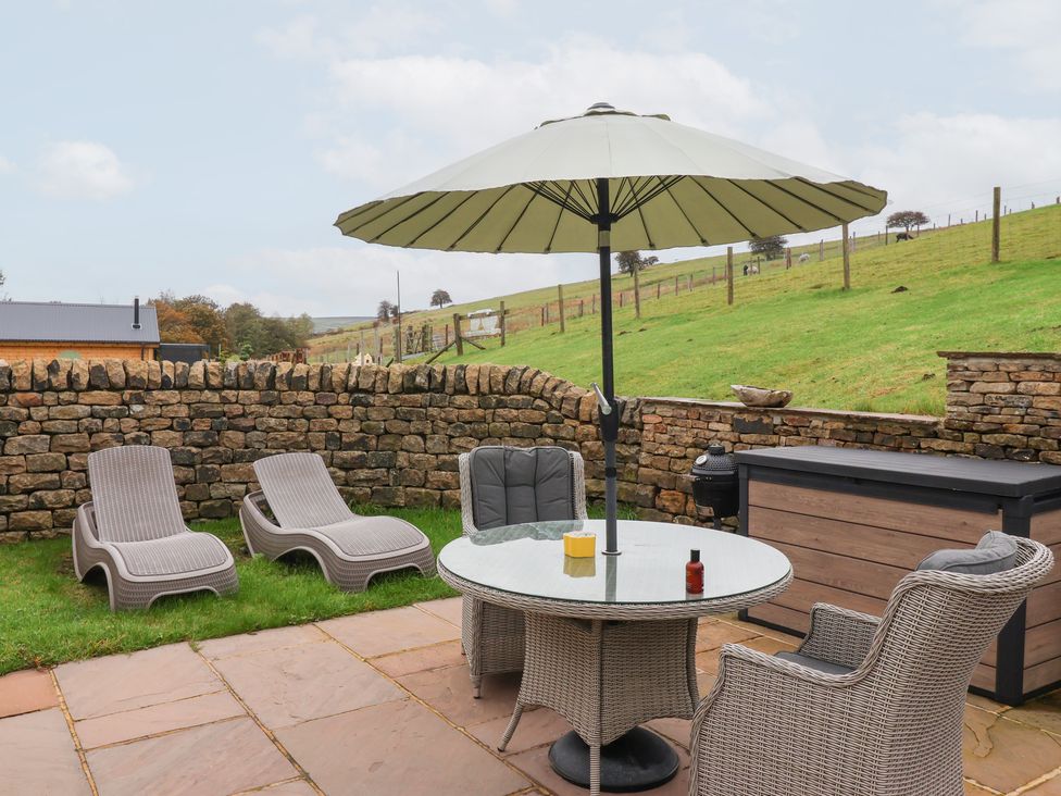 An outdoor area with a table, chairs, and loungers at Beckside Cottage in Cowling near Skipton