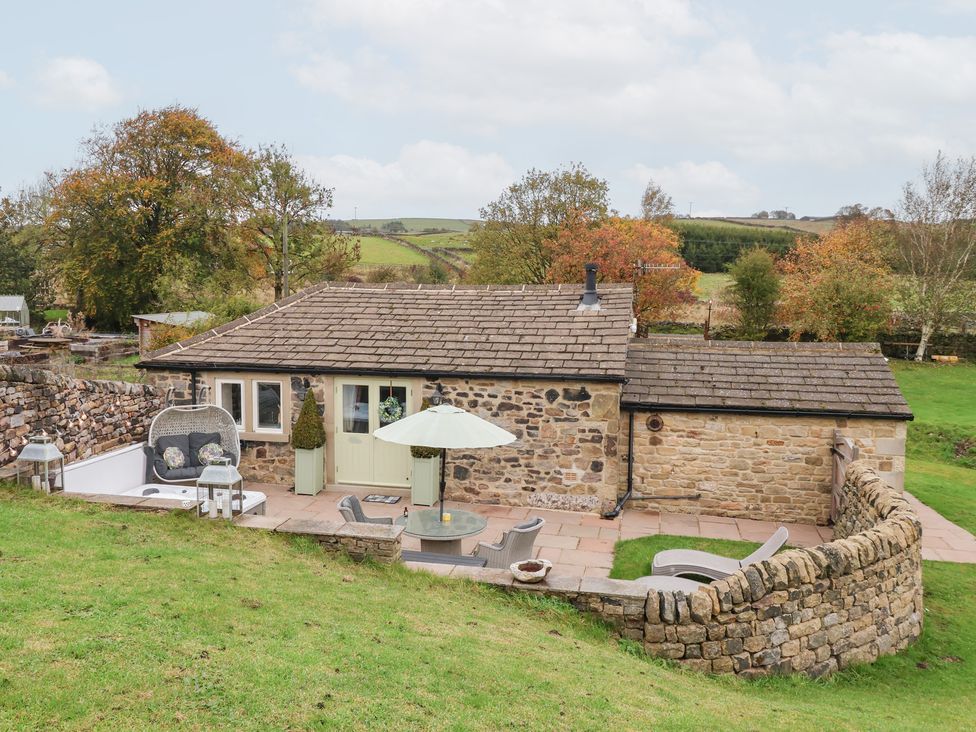 An outdoor space with a cottage, garden furniture and stone wall at Beckside Cottage in Cowling near Skipton