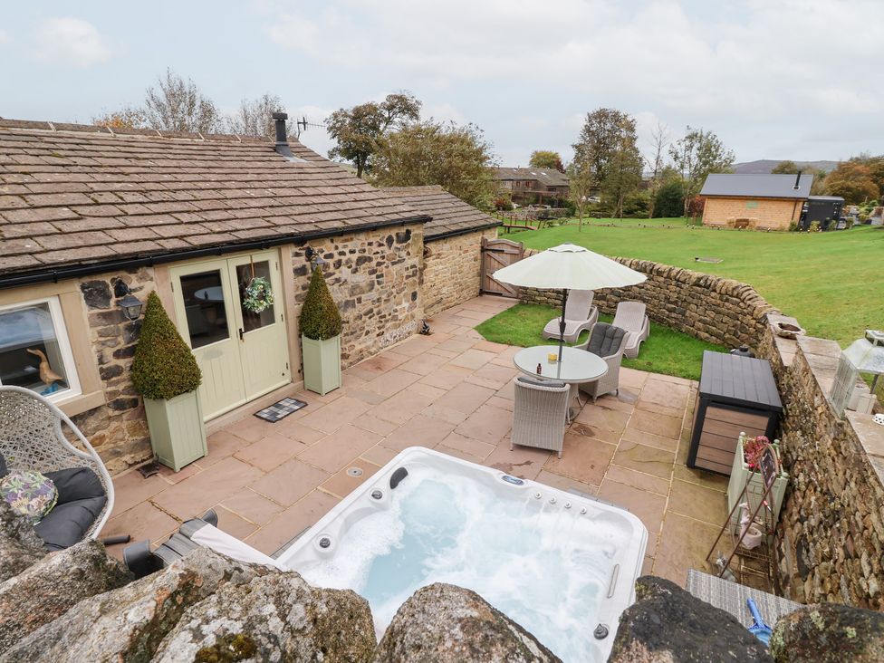 An outdoor area with a hot tub and dining set at Beckside Cottage in Cowling near Skipton