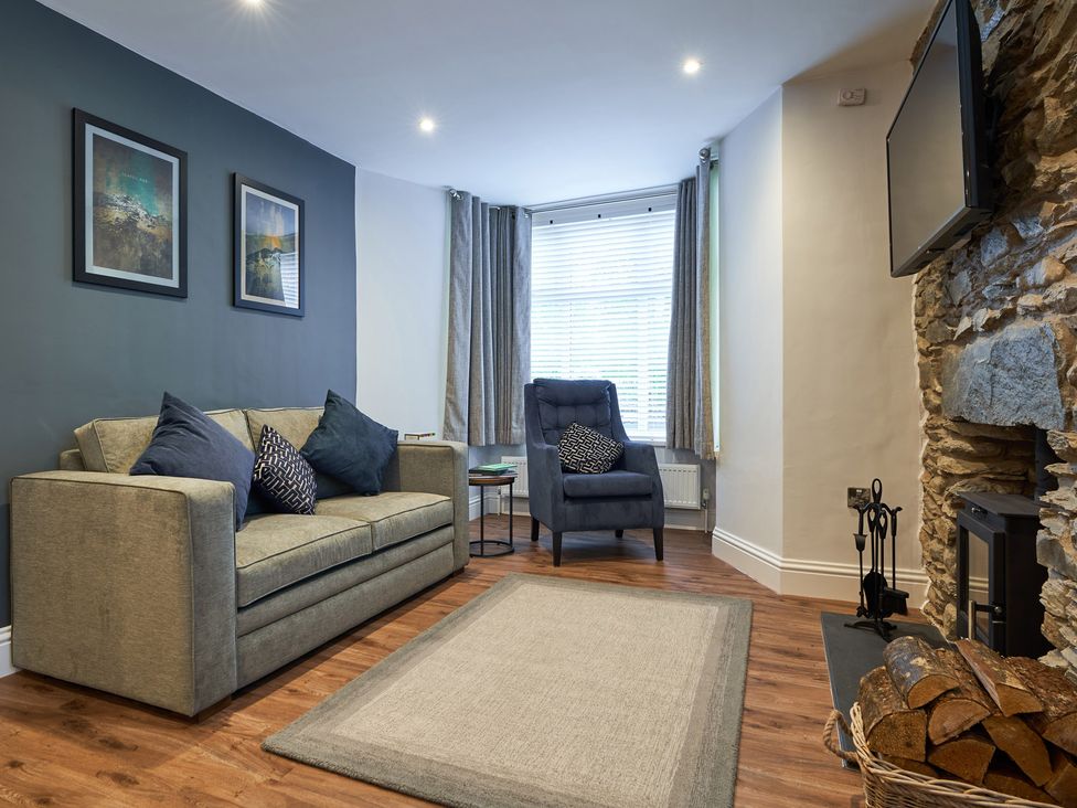 A living room with sofa armchair rug fireplace and TV at Lower Sheriff's Place in Windermere