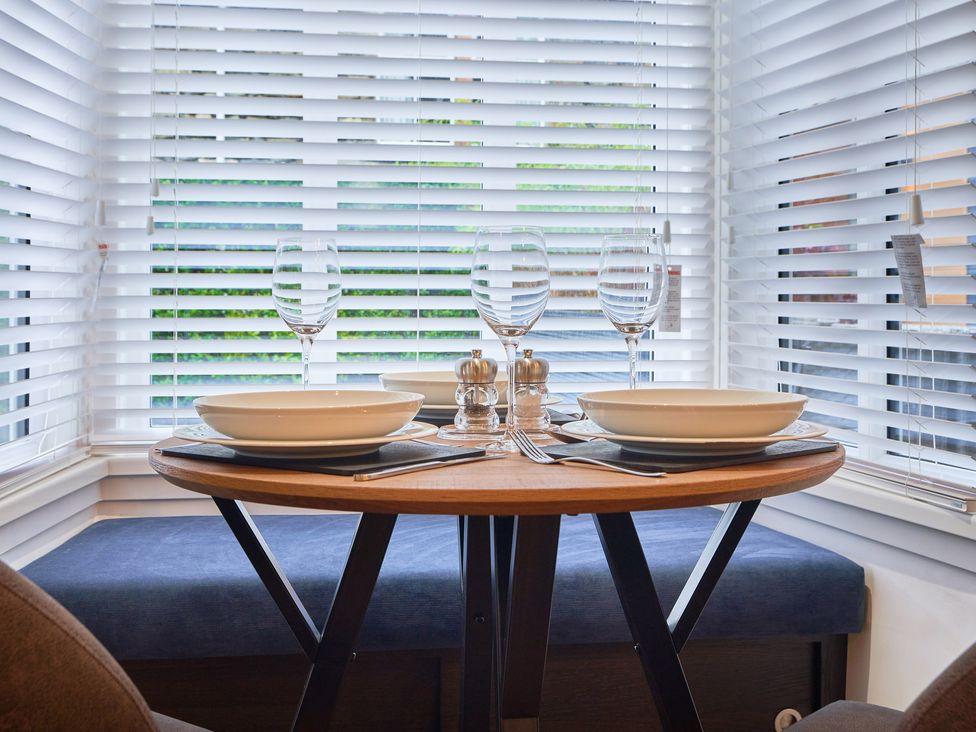 A dining table set with bowls wine glasses salt and pepper shakers by windows with white blinds at Lower Sheriff's Place in Windermere